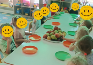 Dzieci przy stolikach przygotowuja sie do wykonania sałatki