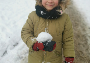 Dziewczynka stoi z kulka śniegu