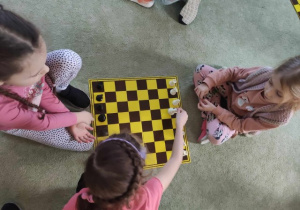 Dzieci siedzą przy szachownicy