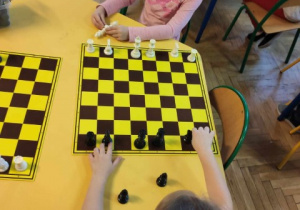 Dziewczynki ustawiają figury na szachownicy