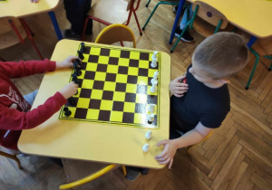 Chłopcy poruszają się figurą szachową