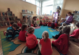 Dzieci słuchają opowiadania czytanego przez Panią bibliotekarkę