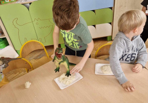 Dzieci odciskają w masie ślady dinozaurów
