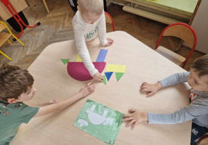 Dzieci ukłądają dinozaury z figur geometrycznych według wzoru