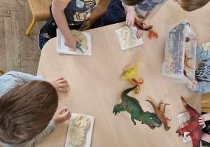 Dzieci odciskają w masie ślady dinozaurów