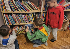 Chłopcy wybierają z półki bibliotecznej książki/