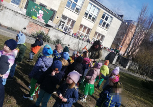 Dzieci przyozdabiają gałązkę kolorowymi bibułami, tworzą gaik.