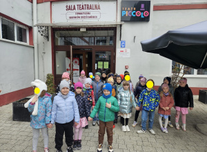 Dzieci pozują do zdjecia przed budynkiem teatru.