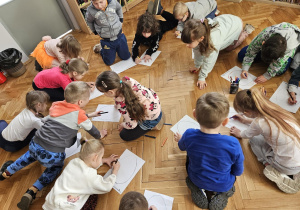 Dzieci ozdabiają kolorowankę pisankę.
