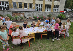 Dzieci kolorują przy stołach.
