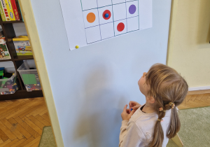 Dziewczynka uzupelnia sudoku kolorowymi kropkami