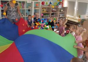 Dzieci bawią się chustą z piłeczkami "Kropeczkami"