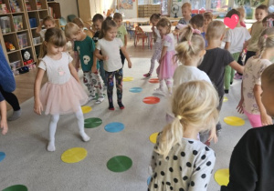 Dzieci biegają po dywanie pośród kolorowych kropek