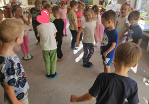 Dzieci stoją nogami na kolorowych kropkach zabawa ruchowa