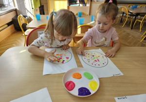 Dziewczynki wypełniają kontur, stemplując go Paluszak mi umoczonymi w farbie.