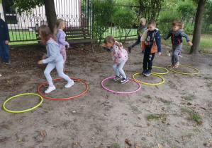 dzieci pokonują tor przeszkód złożony z obręczy i pachołków