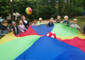 dzieci bawią się z kolorową chustą animacyjną i piłką