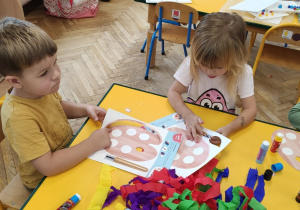 Dziewczynka i 2 chłopców wypychają paluszkami paletę.