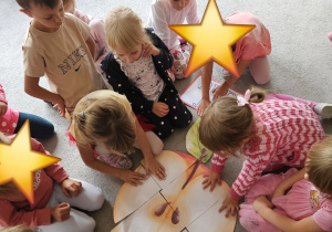 Dzieci na dywanie układają puzzle -jabłko.