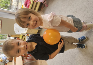 Dziewczynka i chłopiec trzymają balon między swoim brzuszkiem
