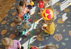 Dzieci siedzą naprzeciw siebie i bawią się piłkami