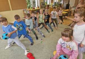 Dzieci wykonują cwiczenia sportowe z piłką, które ucza ich współpracy