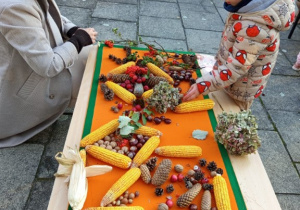 Mama z synem układa jesienny obraz z kukurydzy kasztanów