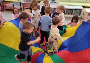 Grupa dzieci bawi się z chustą animacyjną