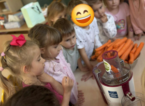 Dzieci obserwują proces wyciskania soku w sokowirówce.