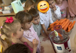 Dzieci obserwują proces wyciskania soku w sokowirówce.