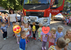 Dzieci pozują do zdjęcia przy wozie strażackim.