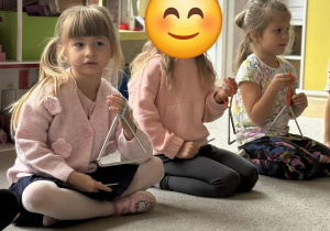 Trzy dziewczynki grają na trójkątach.