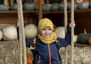 chłopiec na chuśtawce na tle dekoracji z dyń