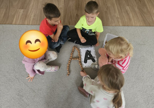 Dzieci układają literę A wg wzoru na kartce.