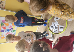 Dzieci stoją wokół obręczy z kierami a.