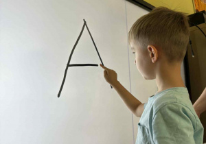Chłopiec pisze literę A na ekranie.