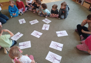 Dzieci podczas zabaw dydaktycznych na dywanie z konturem drzewa