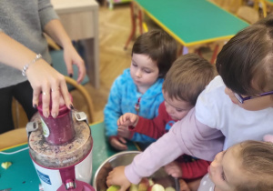 Dziewczynka wkłąda jabłka do sokowirówki