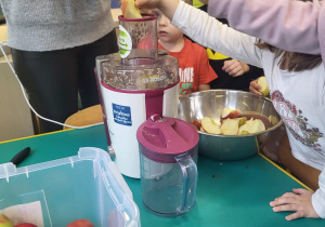 Dzieci wkładają jabłka do sokowirówki