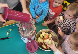 Dzieci wkładają jabłka do sokowirówki