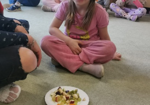 ziewczynka z zasłoniętymi oczami odgaduje jaki owoc zjada