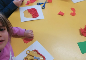 Dzieci bibułą wyklejają kontur jabłka