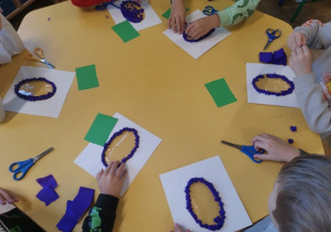 Dzieci bibułą wyklejają kontur śliwki