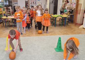 Dzieci turlają dynie pomiędzy pachołkami