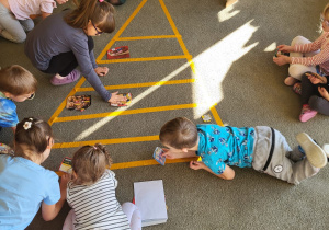 Dzieci układają ilustracje produktów spożywczych na piramidzie żywienia