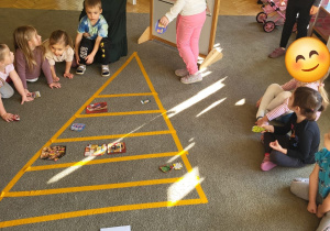 Dzieci układają ilustracje produktów spożywczych na piramidzie żywienia