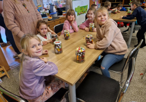 Dzieci wykonują sowę w słoiku wykorzystując kasztany i kolorowe piórka