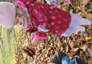 Dziewczynka nawleka liście na patyczek