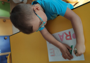 Chłopiec koloruje hasło Nasze prawa