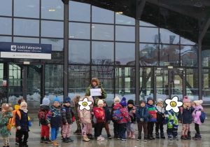 Dzieci stoją przed Dworcem z plakatem logo firmy Elester